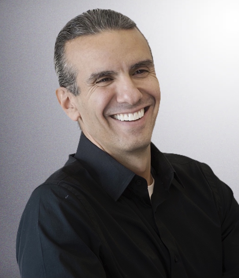 headshot of Dr. Anton Treuer smiling looking away from the camera, wearing a black shirt