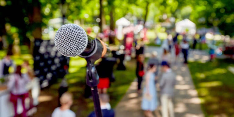 blurry picture of a lot of people gathered in a park and a microphone near by