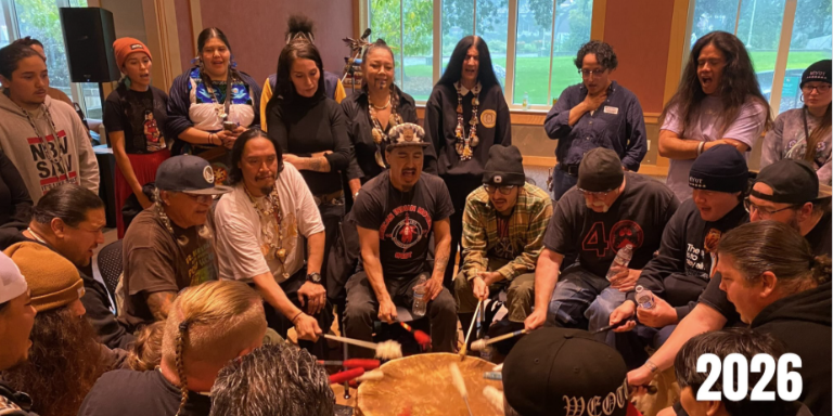 about a dozen people singing around a native drum group
