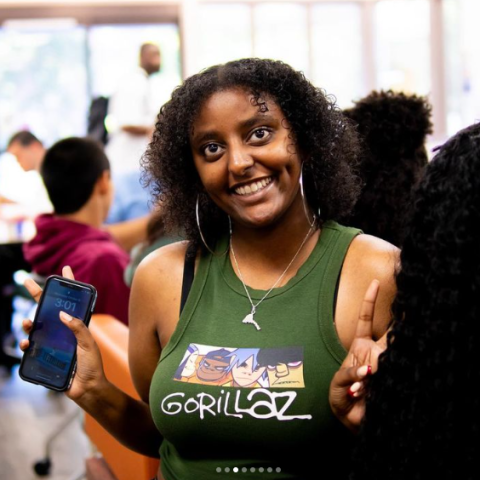 I have mid-length curly hair, am looking into the camera, smile, and am wearing a green shirt.  